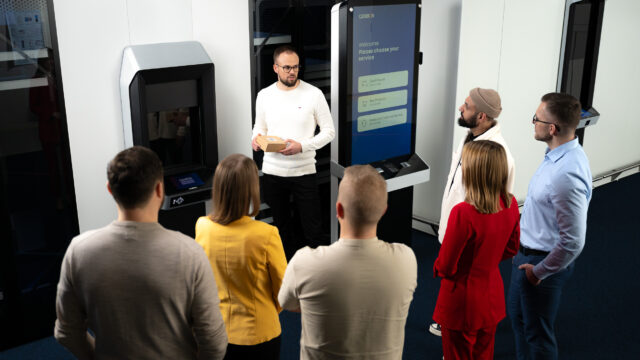 A punch of people standing and listening one person talking about Cleveron parcel robot