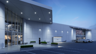 In the twilight, there is a shopping center with a Cleveron parcel locker outside, allowing businesses to securely dispense goods 24/7, and customers can pick up their packages at their convenience.